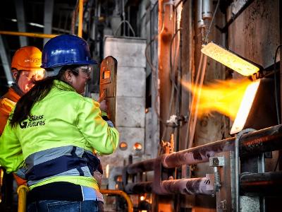 A woman in a Glass Futures hi vis jacket looks at a burning furnace